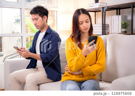 Unhappy asian couple sitting on sofa having relationship problem in living room at home. Unhappy asian couple sitting on sofa having relationship problem in living room at home. 128975608