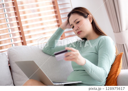 Young asian woman holding credit card or debit card with stress about loan and expense. Young asian woman holding credit card or debit card with stress about loan and expense. 128975617