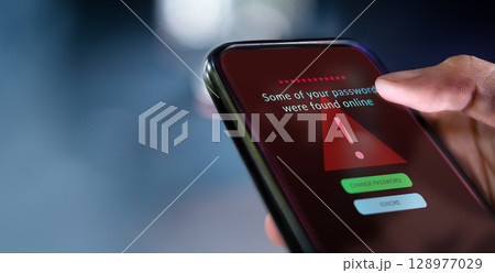 Close up smartphone display with cybersecurity alert, highlighting risks of cybercrime, data breach, and digital vulnerability. red tone Close up smartphone display with cybersecurity alert, highlighting risks of cybercrime, data breach, and digital vulnerability. red tone 128977029