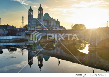 Picturesque view of a cathedral reflected on the water during the golden hour in Ireland. 128977627