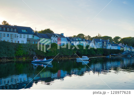 Picturesque coastal village in Ireland with colorful buildings, boats, and reflections in calm water. Picturesque coastal village in Ireland with colorful buildings, boats, and reflections in calm water. 128977628