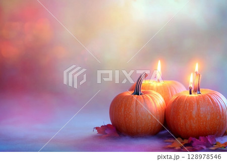Candle lit Halloween pumpkins glowing in vibrant colors with empty space for festive greetings 128978546