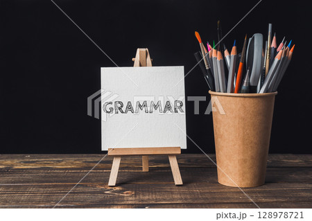 A white sign with the word Grammar written on it is on a wooden table 128978721