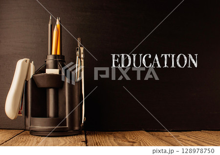 A pencil holder with pencils and a pen sits on a wooden table A pencil holder with pencils and a pen sits on a wooden table 128978750