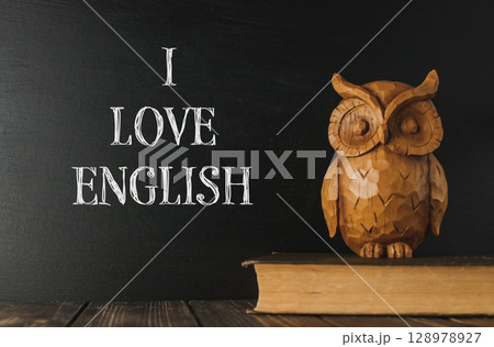 A wooden owl sits on a book with the words I love English A wooden owl sits on a book with the words I love English 128978927
