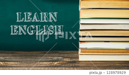 A stack of books with the word learn English written on a green chalkboard 128978929