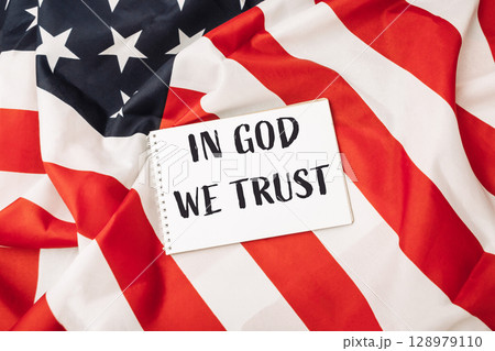 Red and white American flag with a white sign that says In God We Trust 128979110
