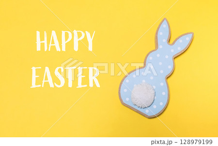 Rabbit with a white tail is on a yellow background Rabbit with a white tail is on a yellow background 128979199