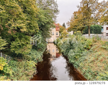 River runs through a forest with a house in the background 128979278