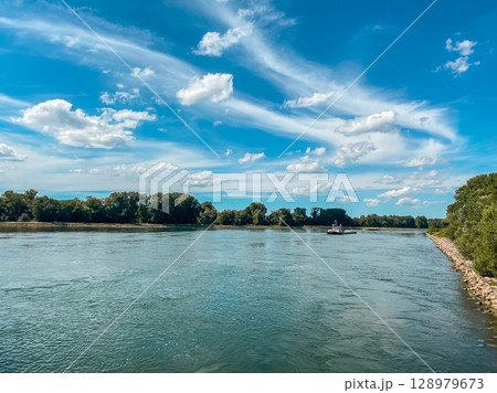 Boat is floating on a river with a blue sky in the background Boat is floating on a river with a blue sky in the background 128979673