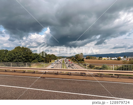 Highway with a bridge over it and a cloudy sky 128979724