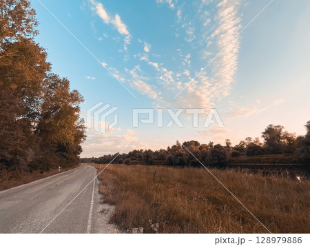 Road with trees in the background and a blue sky 128979886