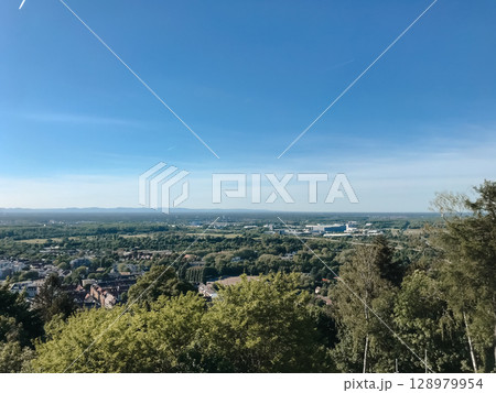 A beautiful blue sky with a few clouds and a city in the distance 128979954