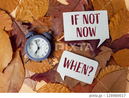 Clock is on a pile of leaves with the words if not now when 128980017