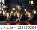 Three light bulbs are lit up and placed on a table 128980264