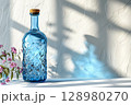 Blue bottle sits on a windowsill next to a plant. 128980270