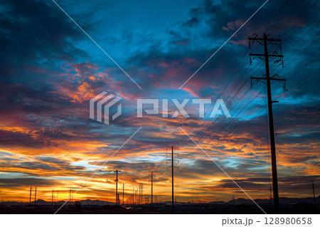 Vibrant Sunset Over Electric Lines and Distant Mountain Landscape. 128980658
