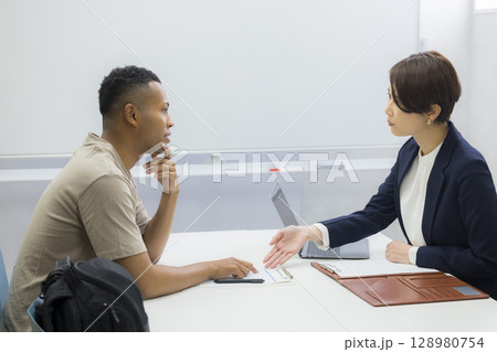 外国人の男性に説明をする女性 128980754