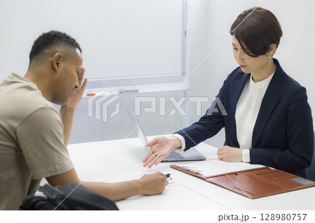 外国人の男性に説明をする女性 外国人の男性に説明をする女性 128980757