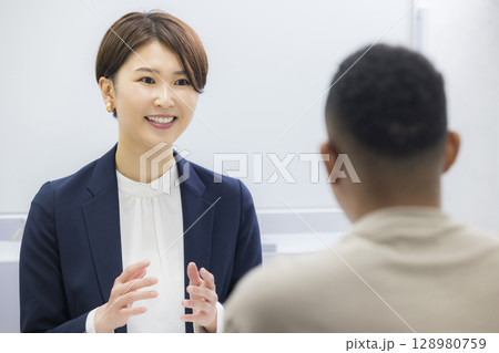 外国人の男性に説明をする女性 128980759
