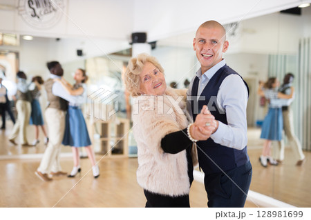 Man and elderly woman performing ballroom dance in dancing room 128981699