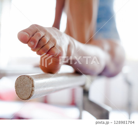 Pointed toes of female gymnast holding position on bars 128981704