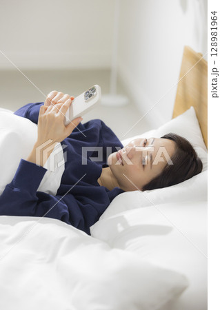 ベッドでスマホを見る女性 ベッドでスマホを見る女性 128981964