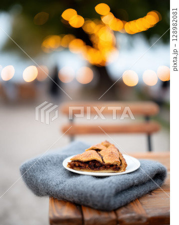 Thanksgiving cranberry pie. Slice of cranberry pie on plate with cozy blanket and bokeh lights in background 128982081