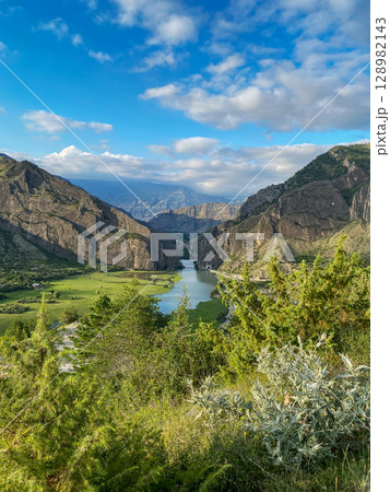 Landscape with beautiful river flowing through green valley and rocky mountains in natural daylight 128982143