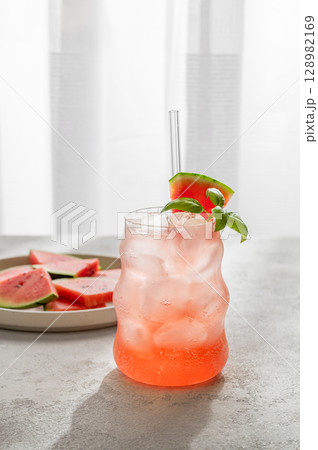 Watermelon mojito cocktail with ice and mint in a glass on a light table near window Watermelon mojito cocktail with ice and mint in a glass on a light table near window 128982169