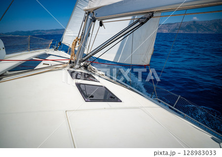 Sailing yacht moving at full speed with all sails up in the open sea near Croatia. Dynamic maritime adventure and freedom of ocean travel. Sailing yacht moving at full speed with all sails up in the open sea near Croatia. Dynamic maritime adventure and freedom of ocean travel. 128983033