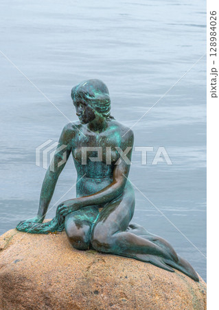 The iconic Little Mermaid statue sits gracefully on a rock in Copenhagen, Denmark. Surrounded by tranquil waters, it offers a serene view for visitors. The iconic Little Mermaid statue sits gracefully on a rock in Copenhagen, Denmark. Surrounded by tranquil waters, it offers a serene view for visitors. 128984026