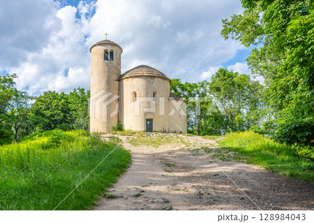 The Romanesque rotunda of Saint George sits atop Rip Mountain, surrounded by lush greenery under a bright blue sky, showcasing historical architecture against a tranquil natural backdrop. The Romanesque rotunda of Saint George sits atop Rip Mountain, surrounded by lush greenery under a bright blue sky, showcasing historical architecture against a tranquil natural backdrop. 128984043