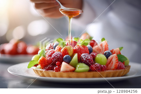 Fresh fruit tart with honey drizzle showing dessert making process in bright kitchen setting with vibrant colors and fresh ingredients 128984256