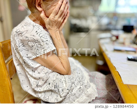 台所で両手で顔をおおう半袖を着た高齢女性 台所で両手で顔をおおう半袖を着た高齢女性 128984450
