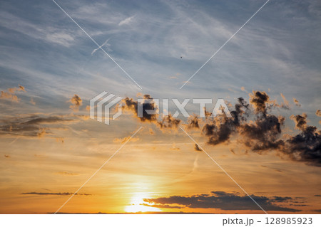 Dramatic sunset sky with scattered clouds Dramatic sunset sky with scattered clouds 128985923