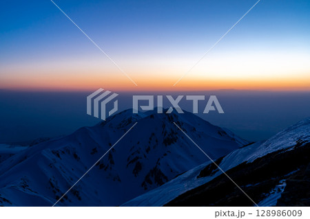 立山の奥大日岳に沈む夕日(剱御前からのブルーアワーの景色) 残雪期の北アルプス立山・別山登山 立山の奥大日岳に沈む夕日(剱御前からのブルーアワーの景色) 残雪期の北アルプス立山・別山登山 128986009