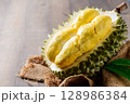 Ripe durian fruit or Durio zibethinus with yellow creamy pulp exposed on wood background. king of fruits 128986384