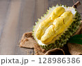 Ripe durian fruit or Durio zibethinus with yellow creamy pulp exposed, isolated on white background. 128986386