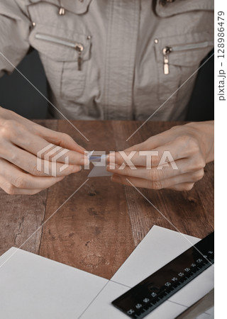 hands of an elderly woman fold origami paper. Creating an origami paper crane 128986479
