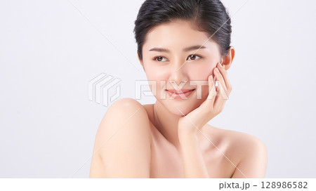 A beautiful young Asian woman with clean, fresh skin against a white background. Skincare, facial treatment, cosmetology, beauty, and spa. An elegant portrait of an Asian woman. A beautiful young Asian woman with clean, fresh skin against a white background. Skincare, facial treatment, cosmetology, beauty, and spa. An elegant portrait of an Asian woman. 128986582