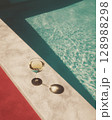 Minimalist Summer Scene with Red Pool Water, Cocktail Glass, and Cement Table in Sunlight 128988298