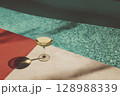 Minimalist Summer Scene with Red Pool, Cocktail Glass, Cement Table, and Shadow Play 128988339