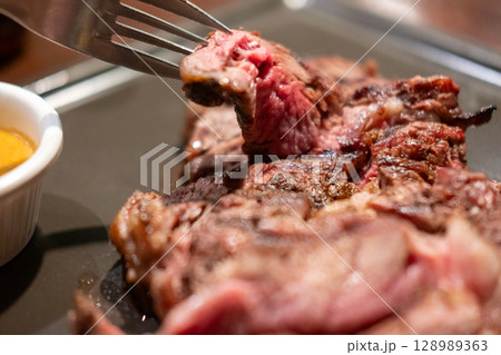 Medium rare rib eye angus steak on a fork 128989363