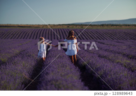 Lavender Women Field. Two women holding hands walking through scenic lavender field at sunset enjoying nature. Lavender Women Field. Two women holding hands walking through scenic lavender field at sunset enjoying nature. 128989643