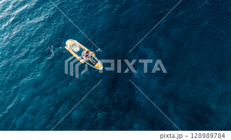 Woman swims on transparent plastic kayak in summer blue sea. Drone view, top down 128989784