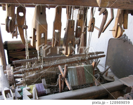A traditional wooden loom with intricate mechanisms and colorful threads in a detailed workshop setting 128989859