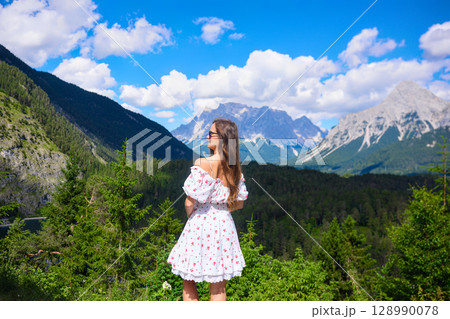 Woman in white dress gazing at mountains 128990078