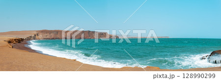 A beautiful beach with a blue ocean and a rocky shore 128990299