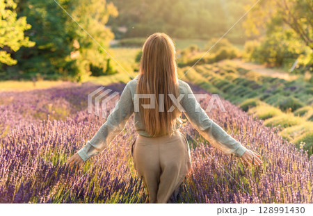 Woman Walking Through Lavender during Sunset 128991430
